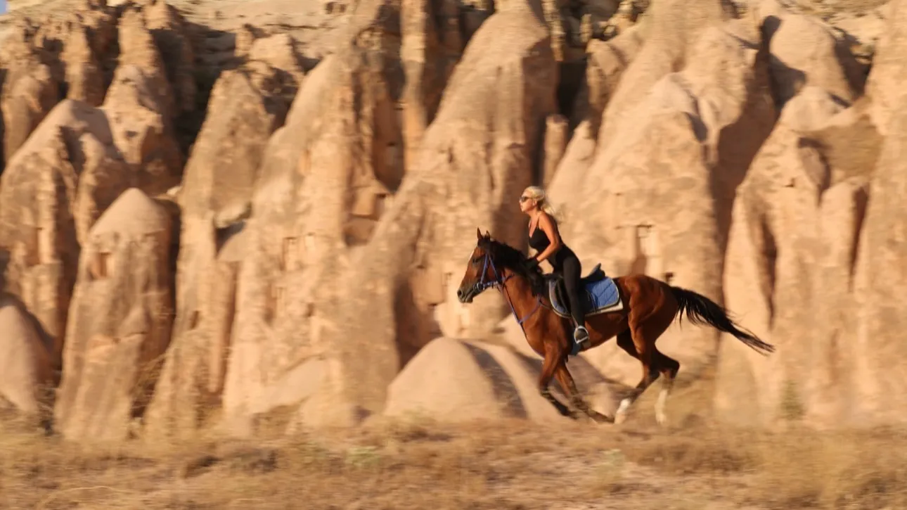 Horse and rider crossing a Cappadocian valley at golden hour